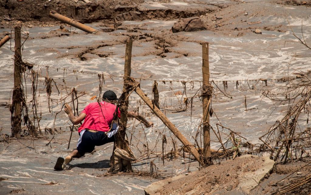 A man tries to reach his home a few weeks after the tidal wave of mud had dried up at the Samarco dam disaster