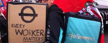A Deliveroo rider at a demonstration with an IWGB flag and a placard that reads 'Every worker matters'. Credit: Owen Espley