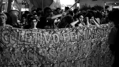 Black and white photo of Brazilian protestors holding a banner that says "Coletivo Feminista Classista Ana Montenegro". Photo: fabio montarroios CC BY 2.0