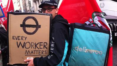 A Deliveroo rider at a demonstration with an IWGB flag and a placard that reads 'Every worker matters'. Credit: Owen Espley
