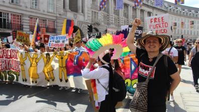 War on Want's Senior Programme's Officer Seb Munoz raises a fist at the front of a colourful Latin American contingent at a rally.